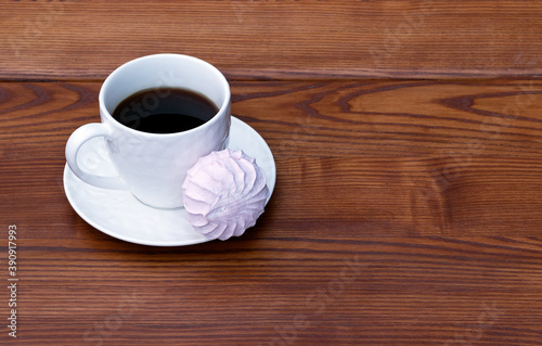 White cup of coffee and pink zefir on the wooden background. Traditional russian sweets like marshmallow. Copy space.