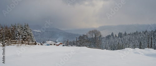 Snowfall over countryside hills, groves and farmlands in winter remote alpine mountain village