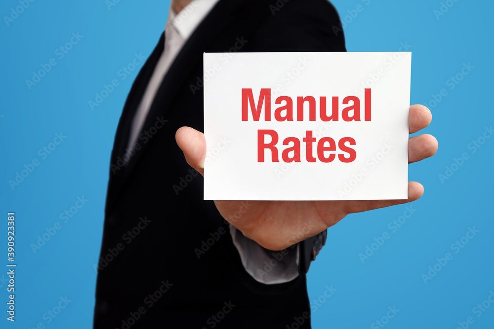 Manual Rates. Businessman in suit showing business card with text. Man isolated on blue background Manual Rates. Businessman in suit showing business card with text. Man isolated on blue background