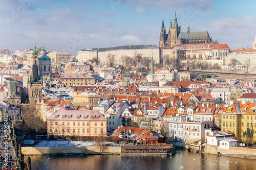 Panoramic view of Prague Castle and Vltava River in winter snow lies on red tiled roofs, Picturesque landscape with Cathedral of St. Vitus and royal palace, Prague, Czech Republic