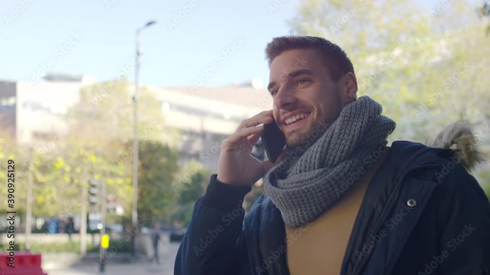 Attractive young man walking in the city and talking on his phone, in slow motion Attractive young man walking in the city and talking on his phone, in slow motion
