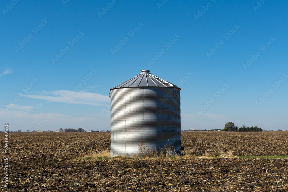 Solitary grain silo on a barren field in the late fall sunshine. Rural Illinois, USA. Solitary grain silo on a barren field in the late fall sunshine. Rural Illinois, USA.