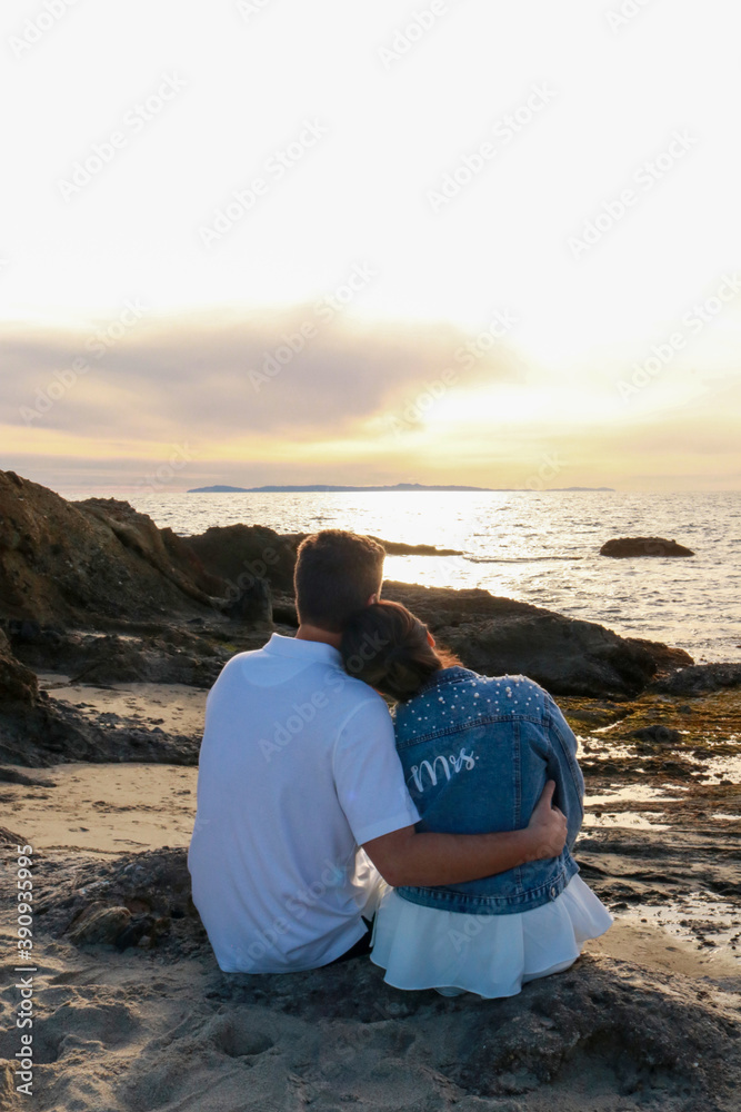 romantic couple sitting on the beach watching the sunset