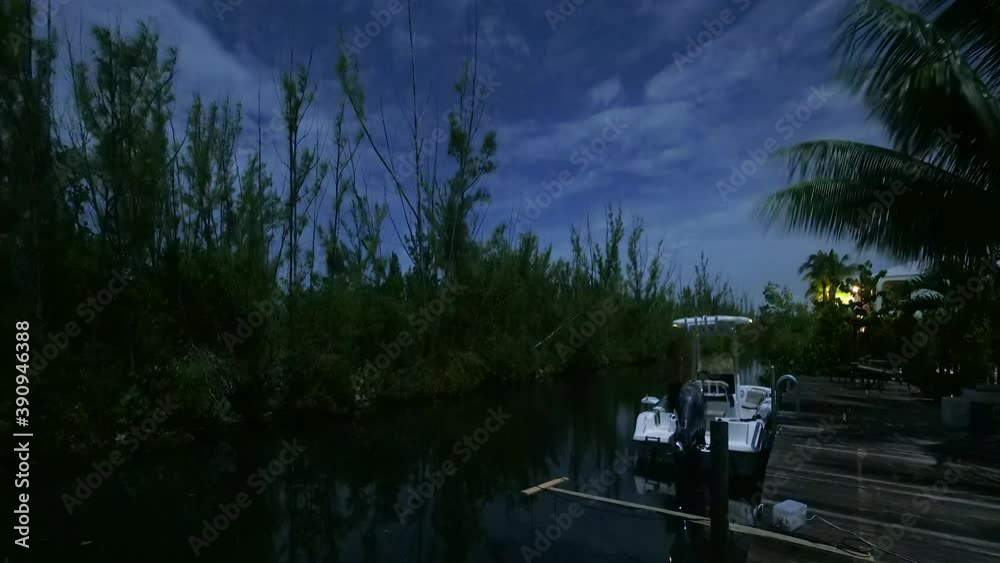 Night time clouds whiz by on a backyard canal during a full moon. Man comes through frame fishing with headlamp on towards the end. Night time clouds whiz by on a backyard canal during a full moon. Man comes through frame fishing with headlamp on towards the end.