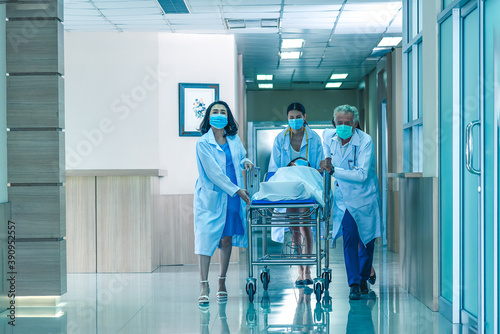 Rear view of doctors running for the surgery.  Hospital Emergency team carrying stretcher with patient through hospital hall.