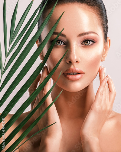 Young beautiful woman with green leaves near body. Skin care beauty treatments concept.  Closeup girl's face with green leaves. photo