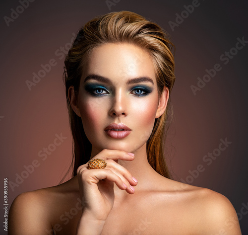 Photo of young woman with style make-up. Portrait of blonde woman with a beautiful face. Closeup face with stylish blue makeup. Fashion model with long hair, studio shot.