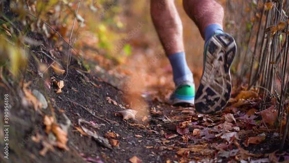 Runner's feet running through leaves on a trail during fall, slow motion Runner's feet running through leaves on a trail during fall, slow motion