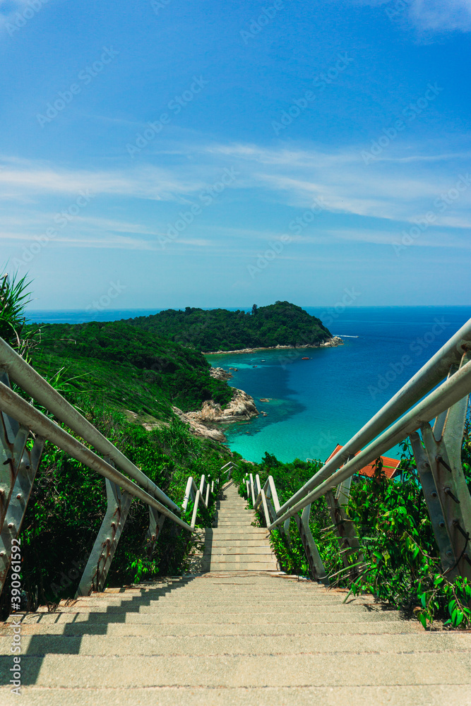 The beautiful scenic view of Small Perhentian Island in Terengganu, Malaysia. The wide view of ocean and green island from the peak of hill. The concrete stairs lead the way to the abandoned jetty.