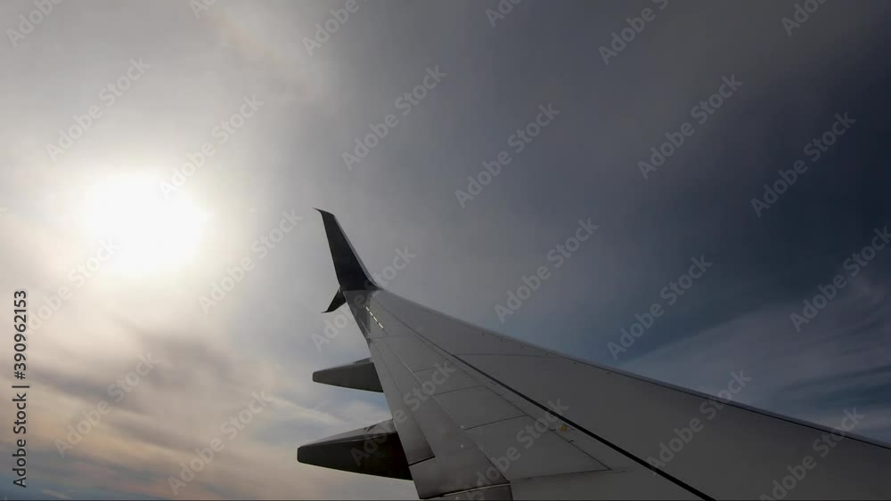 Airplane wing with the sun in the background. Plane making a turn in the sky. Airplane wing with the sun in the background. Plane making a turn in the sky.