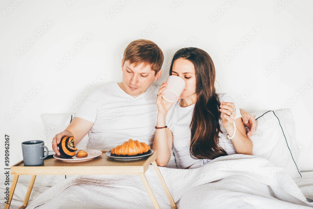 Lazy morning in bed. Lovely couple having breakfast on bed.