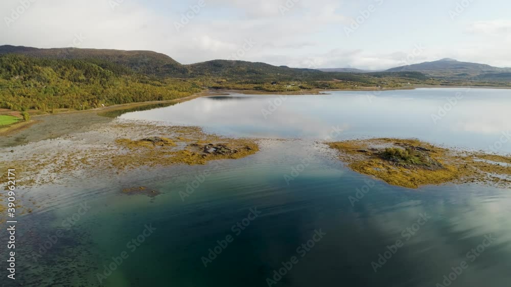 Aerial view of small rocky island, shallow water and alga on the coast of the Senja island, full of autumn colors, in North Norway - tracking, drone shot Aerial view of small rocky island, shallow water and alga on the coast of the Senja island, full of autumn colors, in North Norway - tracking, drone shot