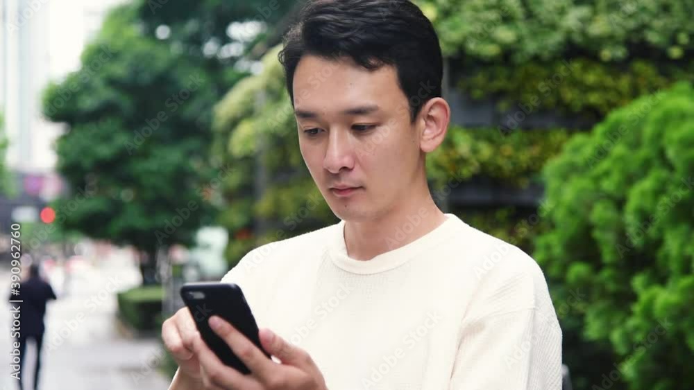 オフィス街でスマートフォンを操作する若い男性
オフィス街でスマートフォンを操作する若い男性