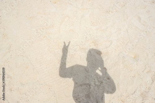 Photographer Making The Peace Sign And Photographing Their Shadow On A Sandy Beach
