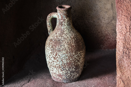 Drinking earthenware jug on stone shelf indoors. photo