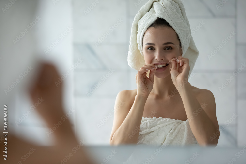 Looking after teeth. Pleasant tidy young lady cleaning teeth with help of dental floss after morning bath procedures, removing pieces of food, following oral hygiene, preventing inflammation caries