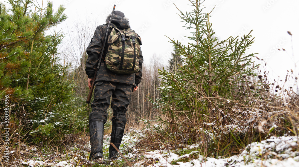 Hunter with a gun and a backpack in the winter forest	
