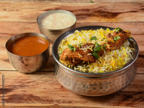 Traditional Hyderabadi Chicken dum Biryani made of Basmati rice cooked with masala spices, served with Onion raita and Salan, selective focus