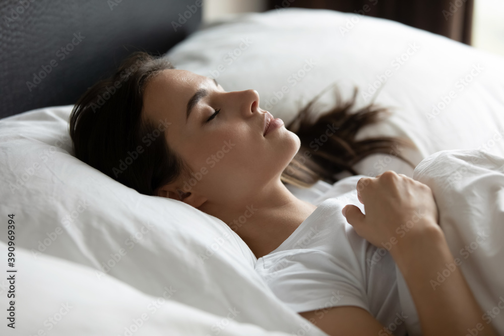 Sleeping beauty. Calm serene young woman lying on back at comfy king size  bed at suite