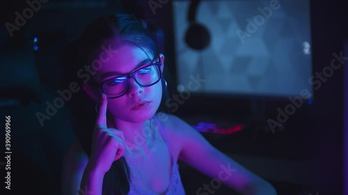 Young attractive woman resettling her spectacles in neon club photo