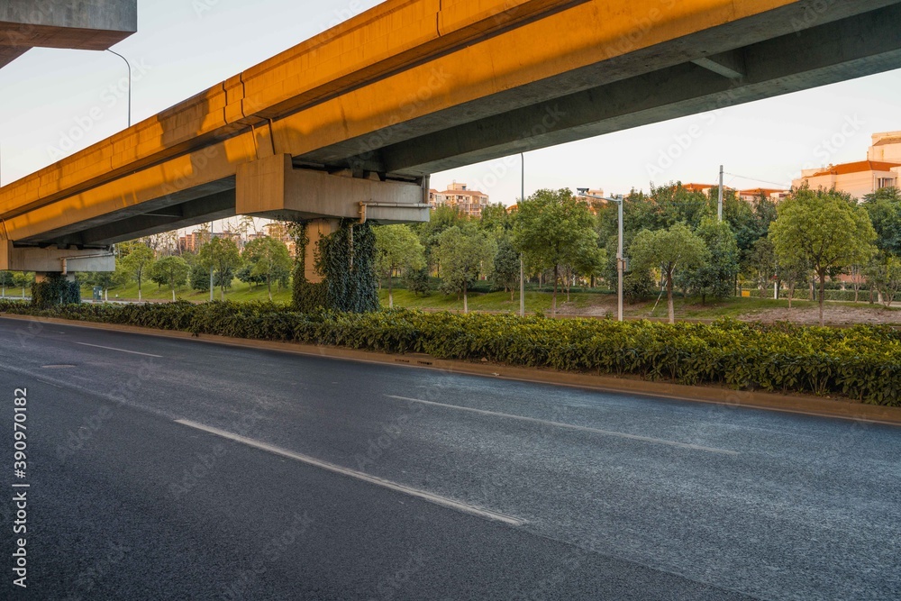 Naklejka premium Urban road under overpass bridge at sunset.