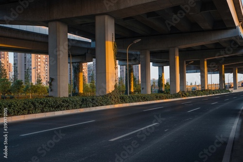 Urban road under overpass bridge at sunset.