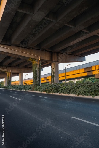 Urban road under overpass bridge at sunset.