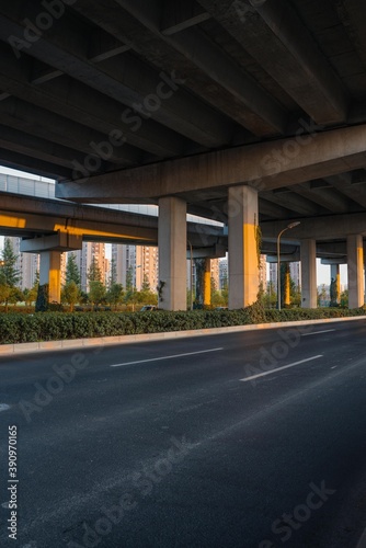 Urban road under overpass bridge at sunset. © Zimu