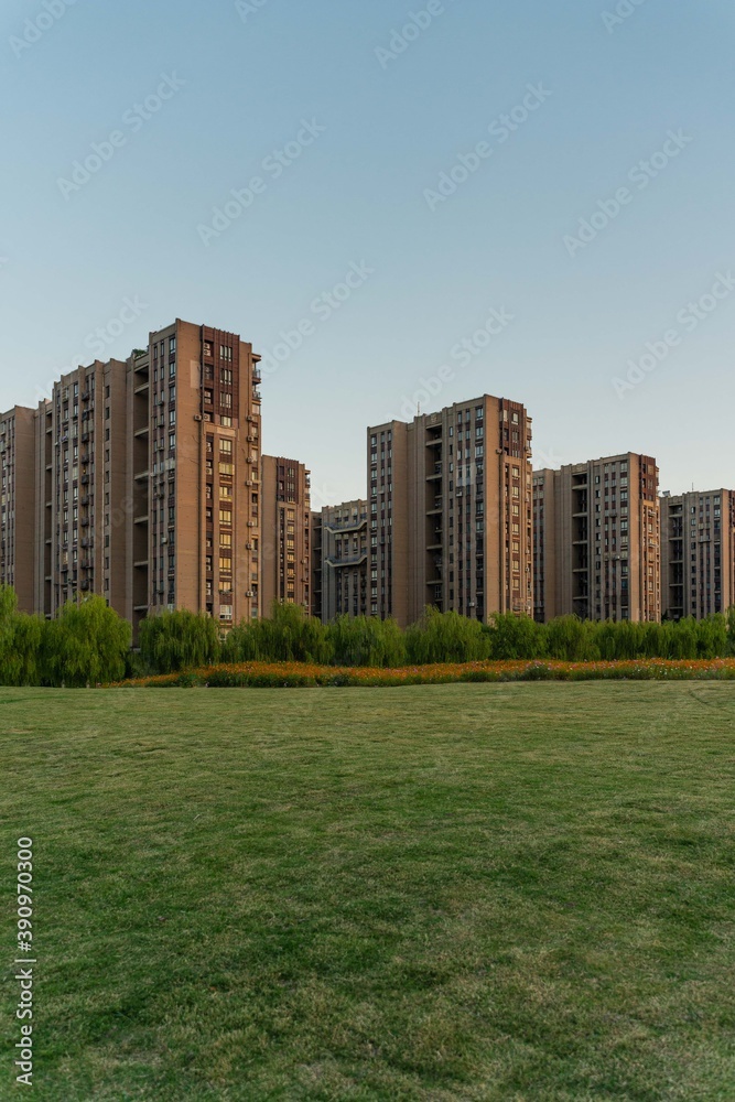 Obraz premium Residential buildings with green grass in front at sunset.