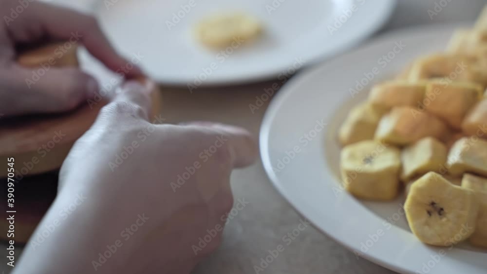Hands use wooden tool to mash flatten and turn banana pieces into tasty chips Hands use wooden tool to mash flatten and turn banana pieces into tasty chips