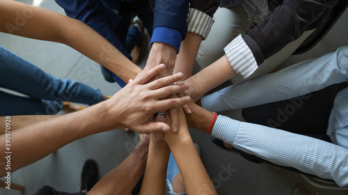 Joining leader. Close up top view of diverse people business partners friends colleagues stacking palms in pile as symbol of racial and gender equality, unity, support of good proposal project startup