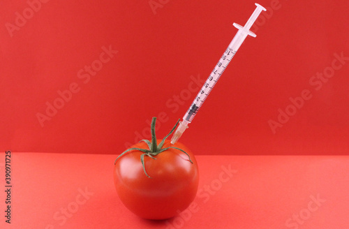 Syringe in red tomato on red background © Valeria F