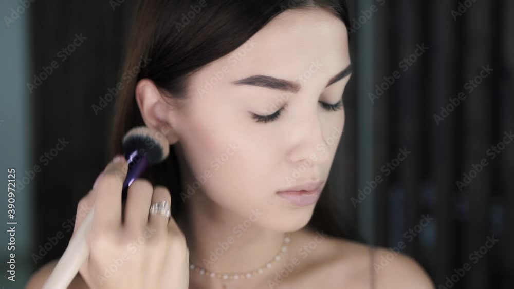 Close-up of slender beautiful young woman model applies powder to her cheeks Close-up of slender beautiful young woman model applies powder to her cheeks