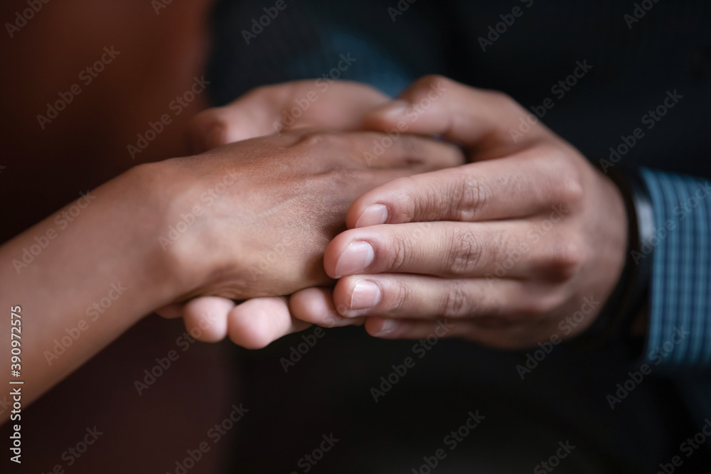 You are not alone. Close up view of male hands holding covering palm of mixed race female expressing care support affection giving hope promising help, biracial family couple reconciling after quarrel You are not alone. Close up view of male hands holding covering palm of mixed race female expressing care support affection giving hope promising help, biracial family couple reconciling after quarrel
