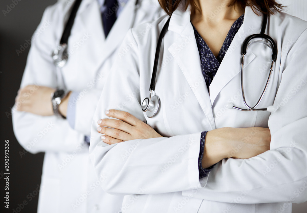 Group of modern doctors standing as a team with arms crossed in hospital office and ready to help patients. Medical help, insurance in health care, best disease treatment and medicine concept Group of modern doctors standing as a team with arms crossed in hospital office and ready to help patients. Medical help, insurance in health care, best disease treatment and medicine concept