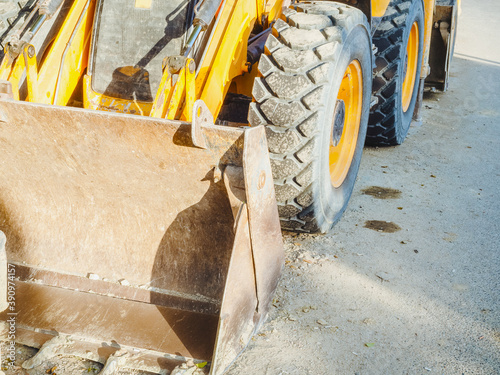 Billede på lærred Fragment of a soiled yellow bulldozer with wheels and a ladle