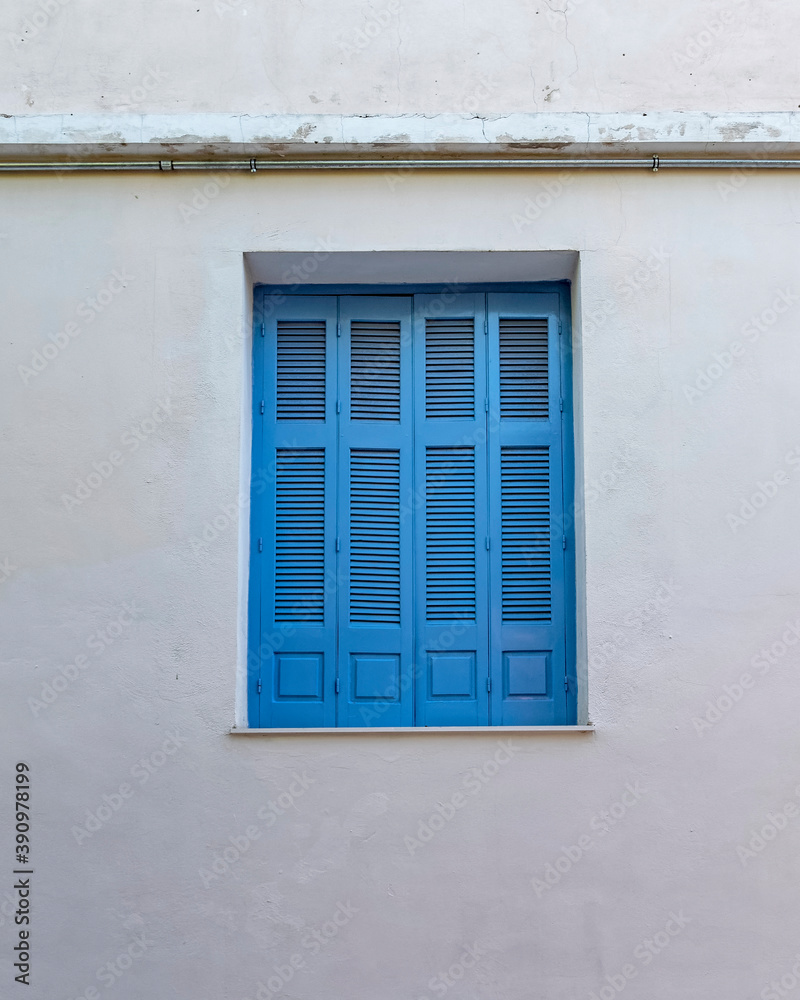 Fototapeta premium Greece, closed blue shutters window on old plastered wall, some space for text
