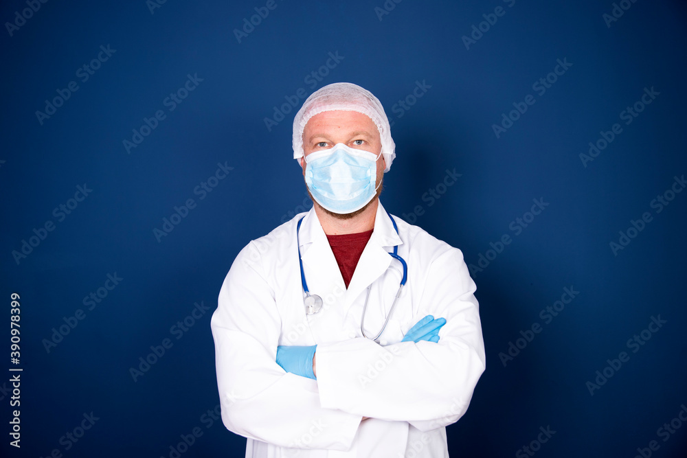 Portrait of male doctor wearing medical mask on blue background.