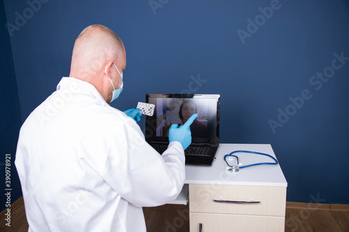 Caucasian male doctor working on laptop consulting patient online, telemedicine concept.