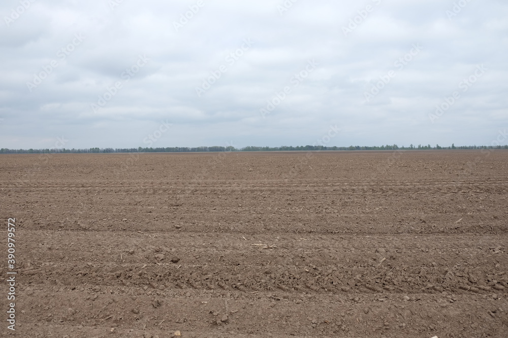 Beautiful sky over a plowed agricultural field. Agro-industrial landscape. A plowed farm field. Cultivated soil during the day. Beautiful sky over a plowed agricultural field. Agro-industrial landscape. A plowed farm field. Cultivated soil during the day.