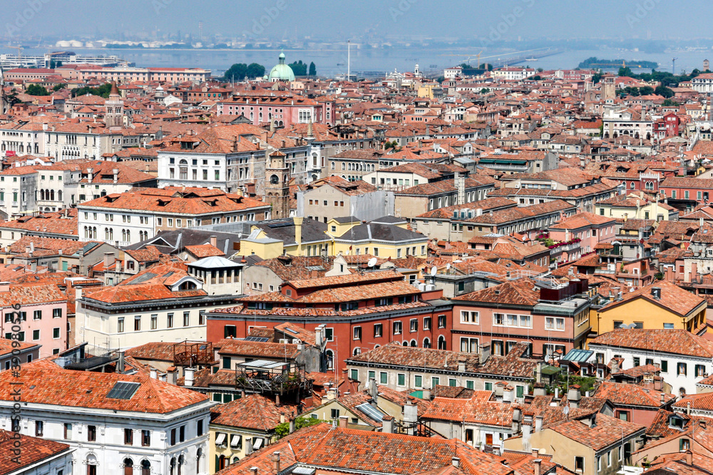 Scenic top view of the old city of Venice, tiled roofs of houses, palaces and cathedrals and the Venetian lagoon