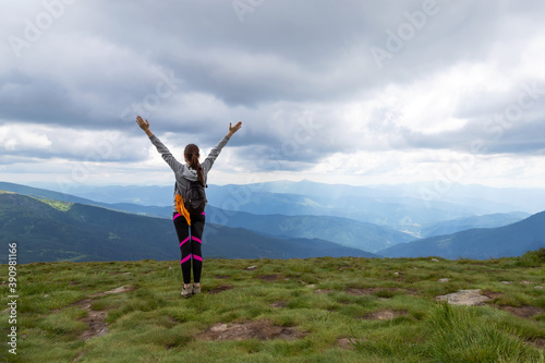Sporty, happy girl with raised arms on the top of the mountain. Tourism.