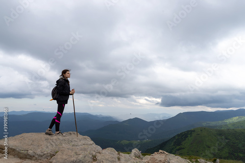 Girl with a backpack on the top of the mountain looks at the beautiful mountains. Success. Tourism.