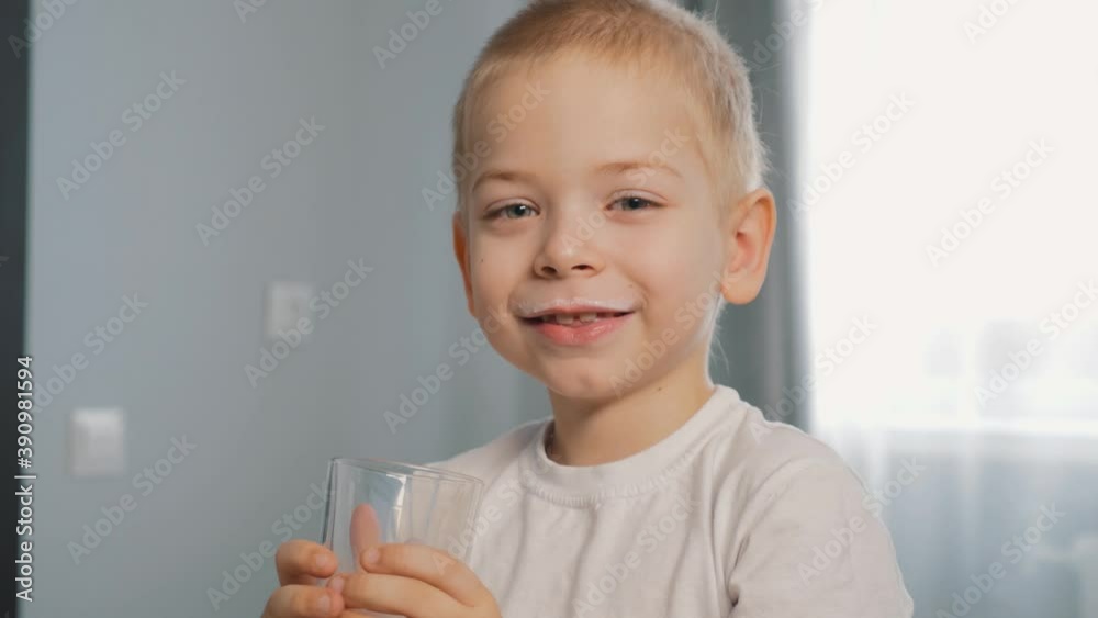 A pretty child drinks milk from a glass Cup. Organic healthy food for children.