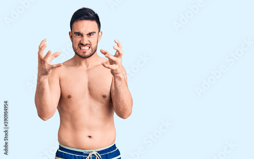 Young handsome man wearing swimwear shouting frustrated with rage, hands trying to strangle, yelling mad © Krakenimages.com