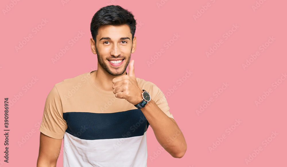 Young handsome man wearing casual clothes doing happy thumbs up gesture with hand. approving expression looking at the camera showing success. Young handsome man wearing casual clothes doing happy thumbs up gesture with hand. approving expression looking at the camera showing success.