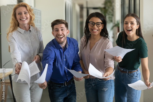 Agreement of century. Group portrait of laughing excited overjoyed business team of diverse corporate employees looking at camera showing confirmed paper document contract result of effective teamwork