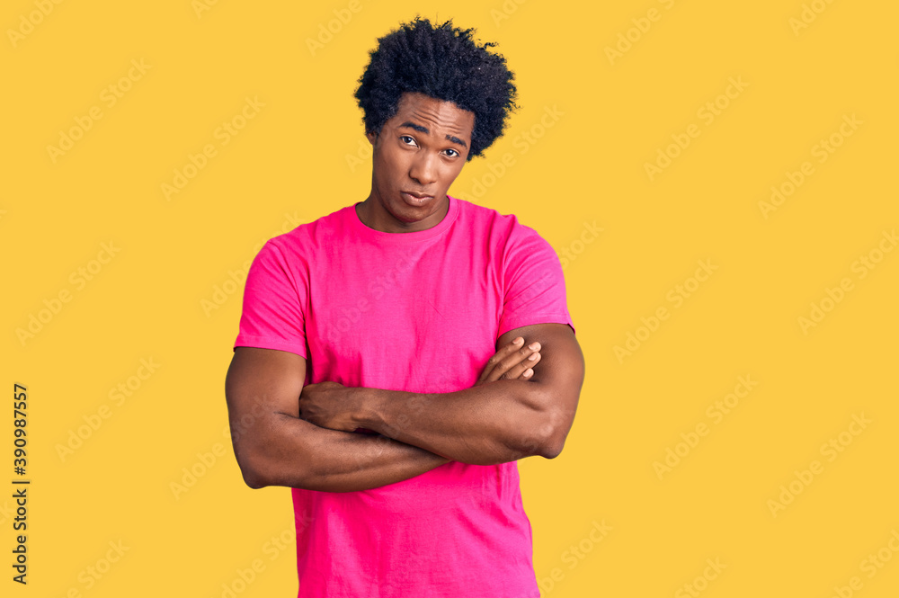 Handsome african american man with afro hair wearing casual pink tshirt skeptic and nervous, disapproving expression on face with crossed arms. negative person. Handsome african american man with afro hair wearing casual pink tshirt skeptic and nervous, disapproving expression on face with crossed arms. negative person.