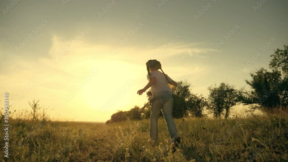 A happy, carefree child runs through a green field, enjoys nature, fresh air. A girl at sunset on a summer day holding a net, a child's toy for catching insects. A happy, carefree child runs through a green field, enjoys nature, fresh air. A girl at sunset on a summer day holding a net, a child's toy for catching insects.