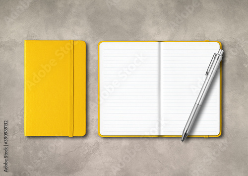 Yellow closed and open lined notebooks with a pen on concrete background